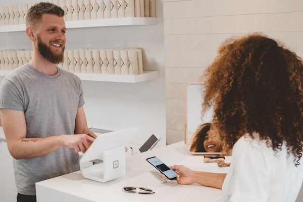 Comerciante atendiendo a una clienta junto a la terminal de consulta de precios Codbar Info!